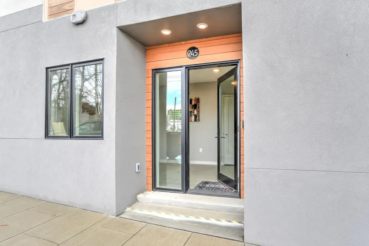 A close-up of an inviting front entrance, featuring a front door with the number 245 and a welcome mat. The threshold suggests moments of arrival and departure, connecting interior comfort to urban exploration.