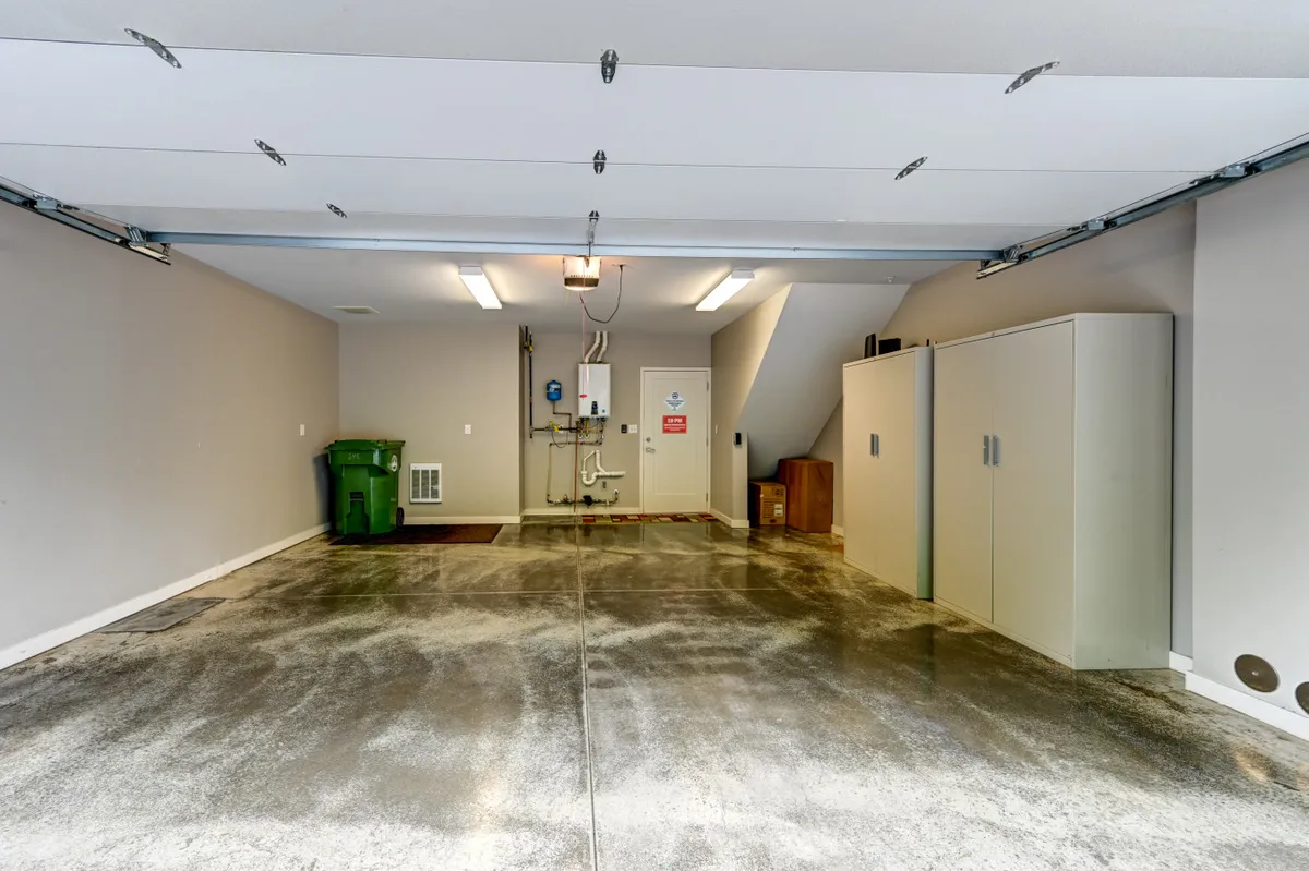 A clean, organized garage interior featuring a raised garage door, storage cabinets, and a utility area—highlighting both functionality and secure parking for two cars.