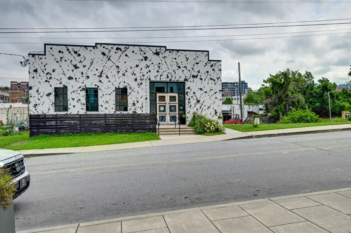 The contemporary facade of a building with a welcoming entrance surrounded by greenery, showcasing the vibrancy and accessibility of the neighborhood. The scene hints at community-oriented spaces nearby.