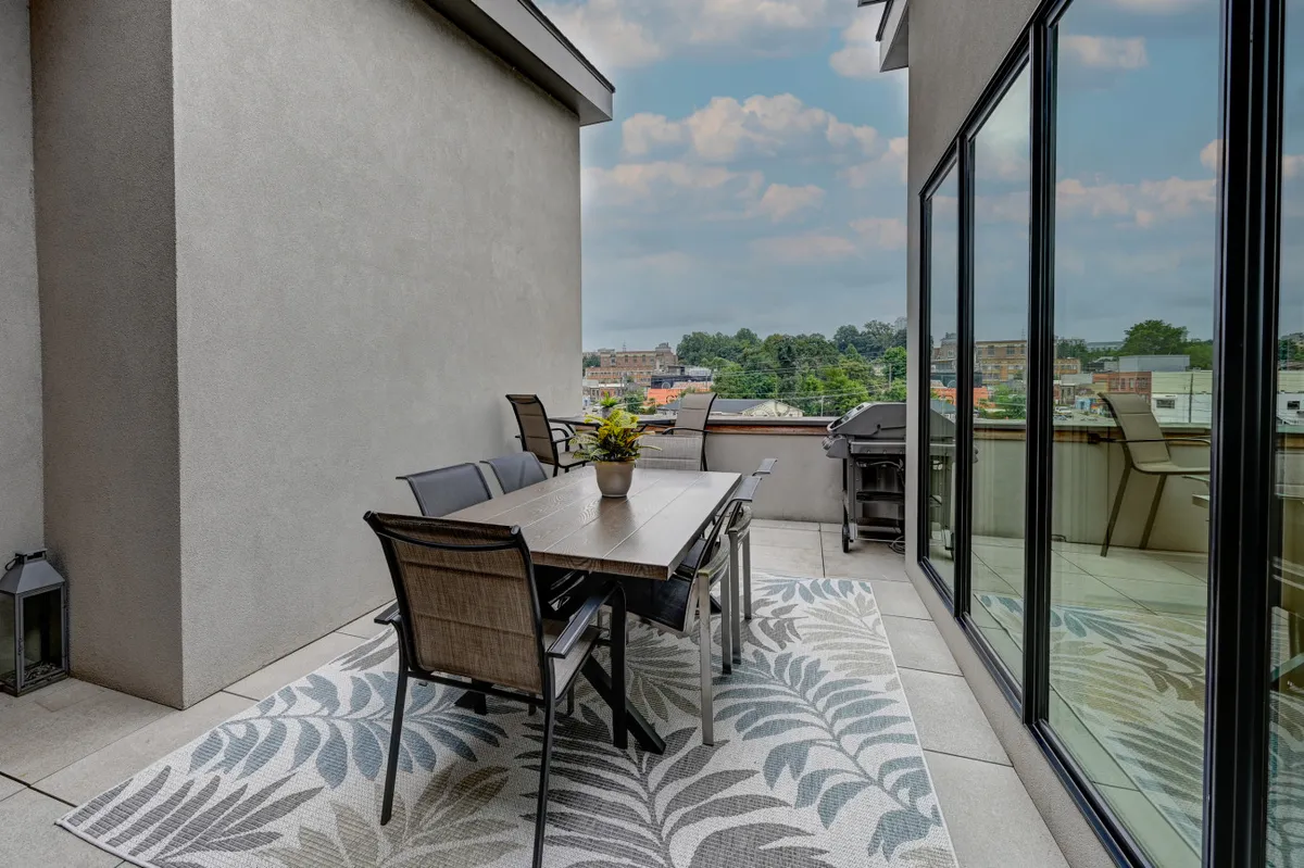 An outdoor dining space featuring a table and seating amidst urban greenery, with large windows connecting the indoor and outdoor environments. The scene is relaxed and casual, perfect for enjoying a sunset meal or unwinding after exploring the city.